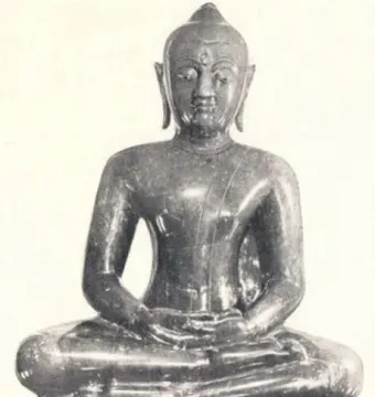 The Emerald Buddha seated on a simple base in meditative posture.
