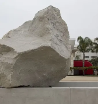 Levitated Mass boulder at LACMA with modern buildings and palm trees behind it