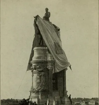Robert E. Lee Monument with an equestrian statue atop a tall ornate pedestal, partly covered by draped fabric, with a crowd gathered below.