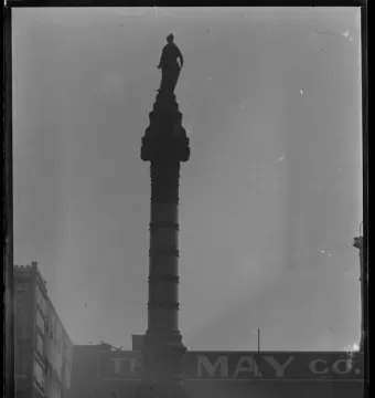 Soldiers\' and Sailors\' Monument column topped by a Liberty figure, with buildings in the background.