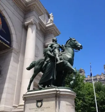 Theodore Roosevelt Equestrian Statue in front of a grand museum building, with Roosevelt on horseback flanked by two walking figures.