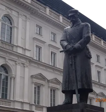Józef Piłsudski Monument in front of a grand historic building with ornate windows and balconies.