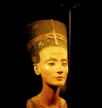 Bust of Nefertiti with a tall decorated crown, broad collar, and one missing eye socket