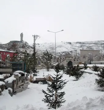 Statue of Humanity with two upright figures reaching toward each other on a snowy hilltop