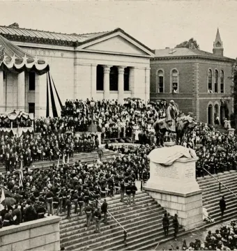Charles Devens equestrian statue on a tall pedestal, surrounded by a large crowd during a public ceremony.