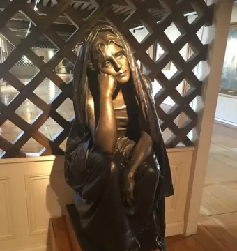 La Douleur, a dark metal sculpture of a seated woman resting her head on her hand.
