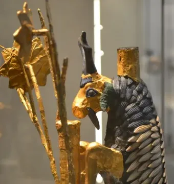 Ram in a Thicket figurine with a golden head, dark horns, and a scale-like body beside a leafy tree.