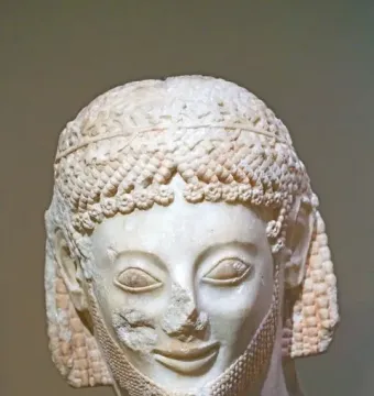 Marble head of the Rampin Rider with elaborate curls, a laurel wreath, and a damaged nose.
