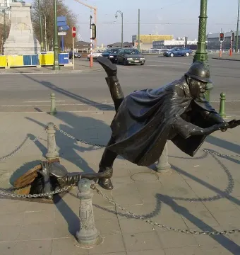 Vaartkapoen bronze statue showing a helmeted figure falling backward as another emerges from a manhole to grab their leg.