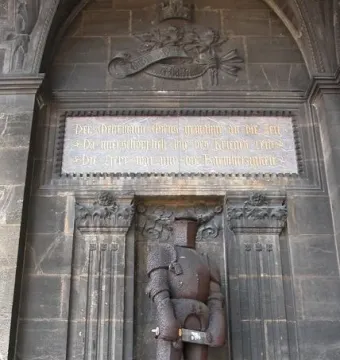 Wehrmann in Eisen, a dark knight statue in full armor holding a sword beneath a stone archway.
