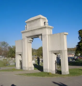 Confederate Memorial Gateway with a large central arch and two smaller side arches beside a cemetery road.