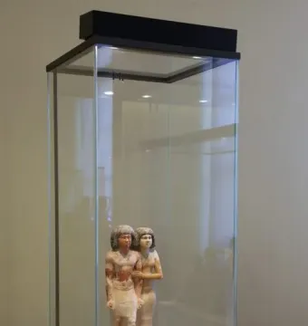 Ancient Egyptian statue of Raherka and Meresankh standing together in a glass display case.