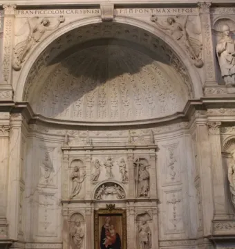 White marble statue of Saint Peter in the Piccolomini Altar at Siena Cathedral, shown in a twisting pose with a book held in his left arm.
