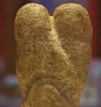Ain Sakhri Lovers stone sculpture with two rounded lobes on a dark base.