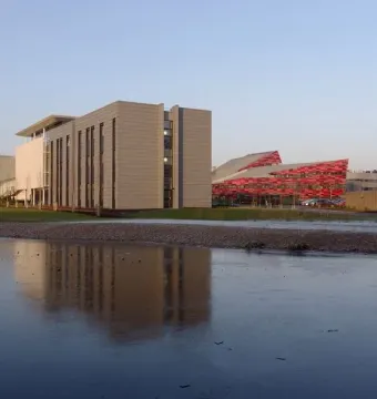 Aspire, a tall red lattice steel sculpture, rises beside a partially frozen lake.