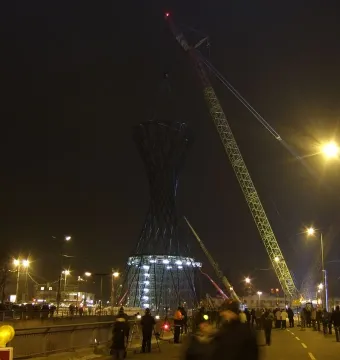 The Mae West sculpture stands lit at the base as a crane rises above it during nighttime construction.