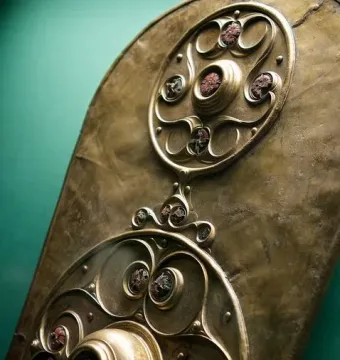 The Battersea Shield with two circular bosses and intricate swirling bronze patterns.