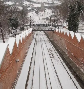 Snow-covered funicular railway descending between brick walls on Buda Castle Hill.