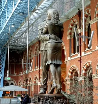 The Meeting Place bronze sculpture of a man and woman embracing inside a large vaulted hall.