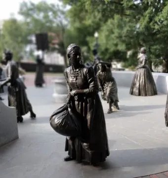 Virginia Women\'s Monument sculptures of women in period clothing on a stone plaza surrounded by trees.