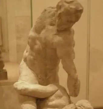 Michelangelo\'s Two Wrestlers sculpture showing two intertwined male figures wrestling on a dark wooden base.