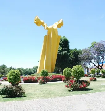 Ángel Custodio sculpture with bright yellow abstract forms in a landscaped park.