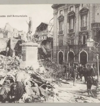 The statue of John of Austria stands on a tall pedestal amid earthquake rubble in a devastated square, with several people nearby.