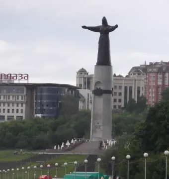 The Mother Patroness statue stands on a tall pedestal with outstretched arms, reached by steps and fountains.