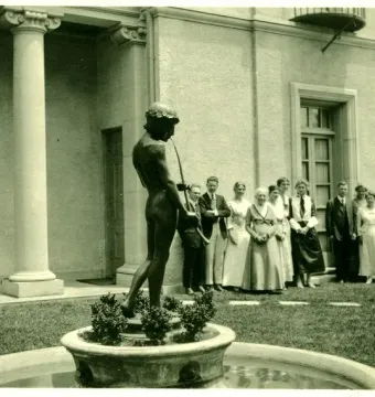 The Spirit of Spanish Music sculpture shows a dark male figure wearing a head wreath and playing a long flute in a fountain basin.