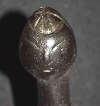 Close-up of the Venus of Langenzersdorf showing the elongated head, incised facial lines, and slender neck.