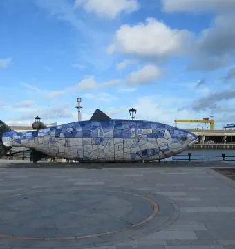 The Big Fish mosaic sculpture on a waterfront promenade beside the river in Belfast.