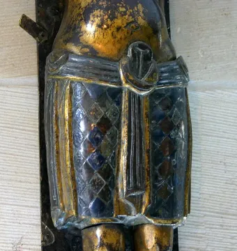 Close-up of the Mindener Cross showing a bronze figure’s diamond-patterned loincloth.