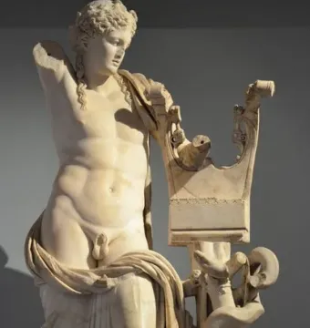 Apollo of Cyrene marble statue holding a lyre stand with a coiled serpent, shown with one arm missing.