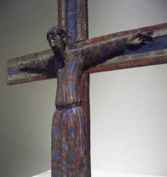 Batlló Majesty, a painted wooden crucifix sculpture with a robed figure, outstretched arms, and red and blue decorative patterns