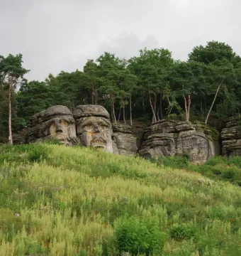 Devil\'s Heads carved into sandstone outcrops on a wooded hillside.