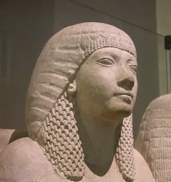 Detail of the Horemheb and Amenia limestone statue showing the husband’s head and upper torso in profile, with a second figure partly visible.