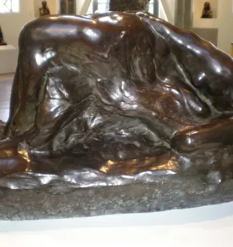 Illusions Received by the Earth sculpture showing two intertwined reclining bronze bodies against a rugged base.