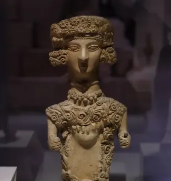 Lady of Ibiza terracotta statuette with an elongated neck, stylized face, and ornate patterned headpiece.
