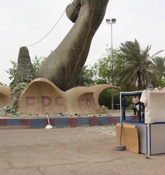 Base of the Victory Arch with wave-like sculpted forms, green debris, and red F.P.S. lettering beneath a dark curved arm and spiky conical structure.