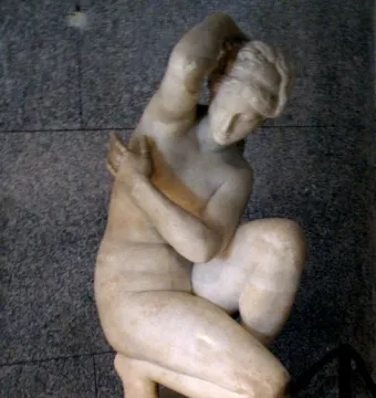 Crouching Venus marble sculpture of a nude female figure in a crouching pose on a base.
