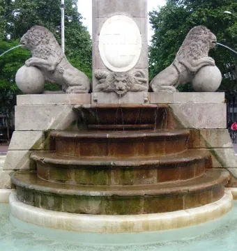 Fountain of Hercules with two carved lions on spheres spraying water into a stone basin.