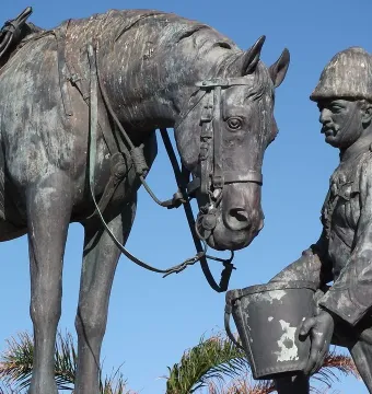 Close-up of the Horse Memorial showing a uniformed soldier in a pith helmet offering a bucket to a saddled horse.