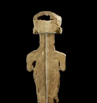 Back view of the Lady of Ibiza clay figure with a rough surface and a metal support rod.