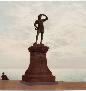 Leif, the Discoverer statue on an ornate pedestal overlooking the water, with two people seated nearby.