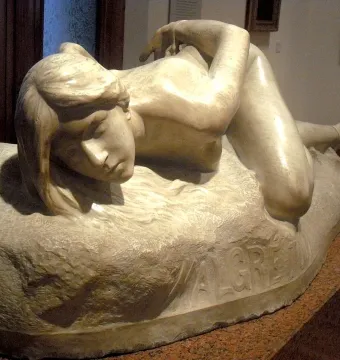 Malgré Tout, a light-colored stone sculpture of a reclining nude female figure on a rough base with the inscription \