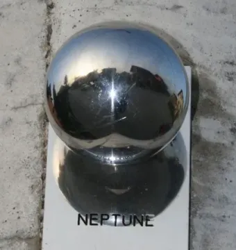 Neptune plaque beside a shiny metallic sphere mounted on a grey wall.