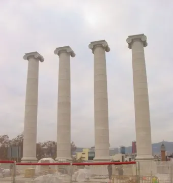 The Four Columns standing behind a fenced construction site under an overcast sky.