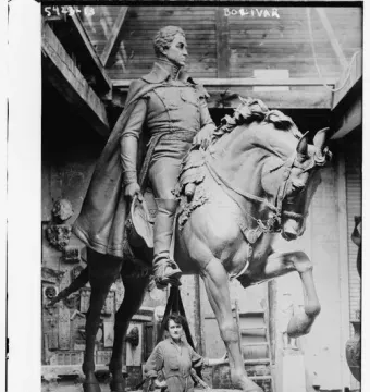 Black and white photograph of the Simón Bolívar equestrian statue with a worker standing beside its base.