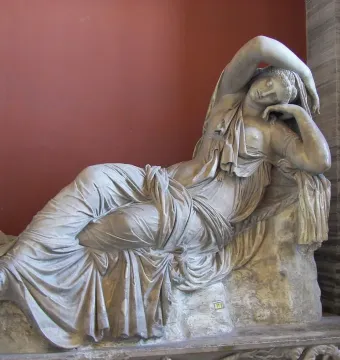 Sleeping Ariadne reclining in white marble with draped fabric and one arm raised over her head.