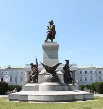 Tadeusz Kościuszko Monument with a bronze figure on a pedestal, flanked by additional sculptures including an eagle in a grassy park.